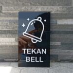 Akrilik sign tekan bell custom bening elegan di meja kasir.